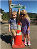 Children Smiling Next to a Cone in Front of the Greenway for a Day Sign