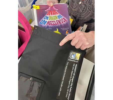 Library staff places a book into an Oregon City Library By Mail bag